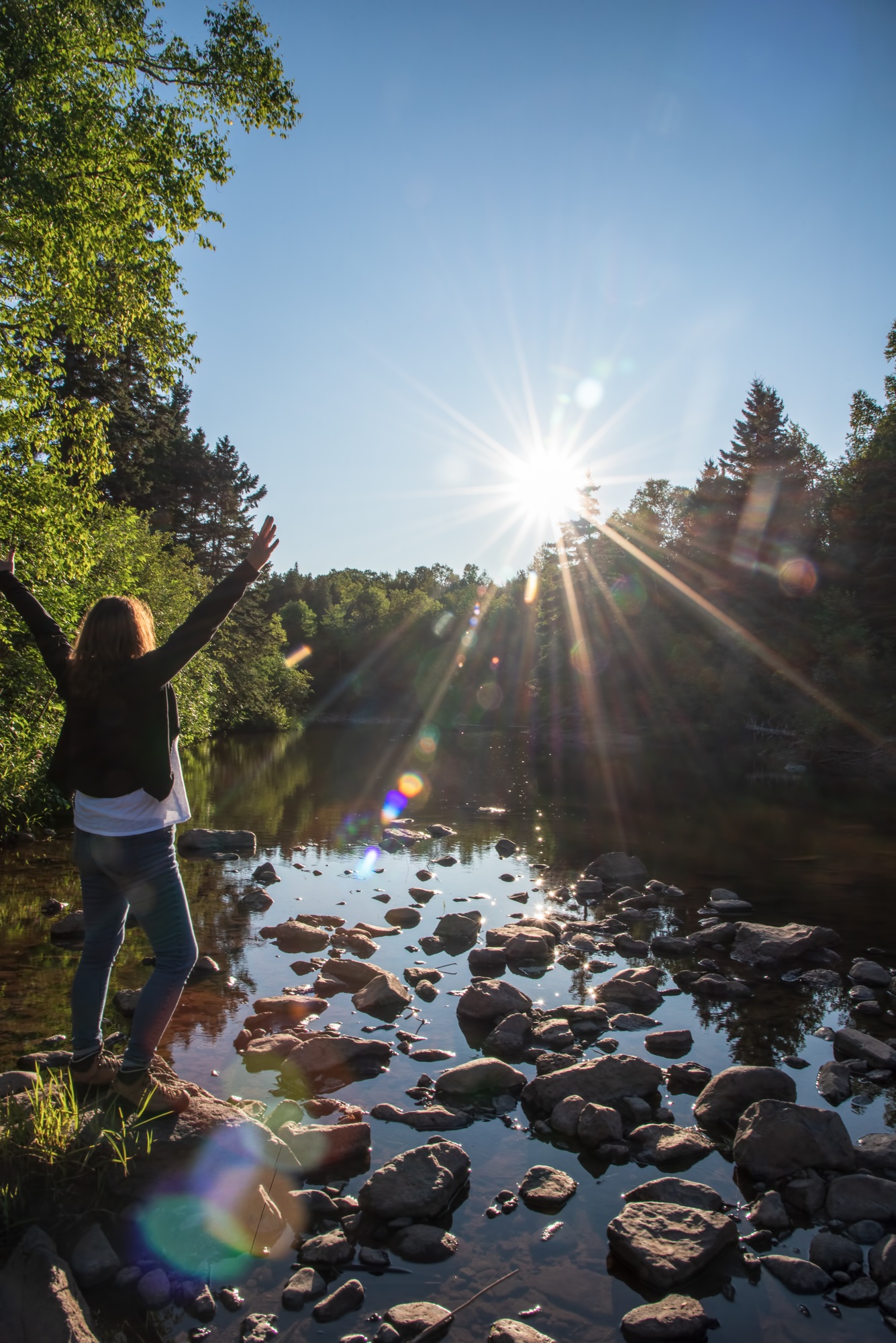 Woman with arms raised into bright sun on MInnesota outdoor adventure